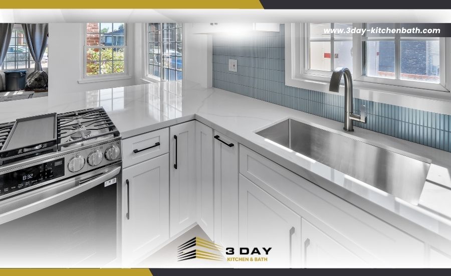 Close-up of a modern kitchen remodel featuring a large stainless steel undermount sink, light blue backsplash, and the 3 Day Kitchen & Bath logo.