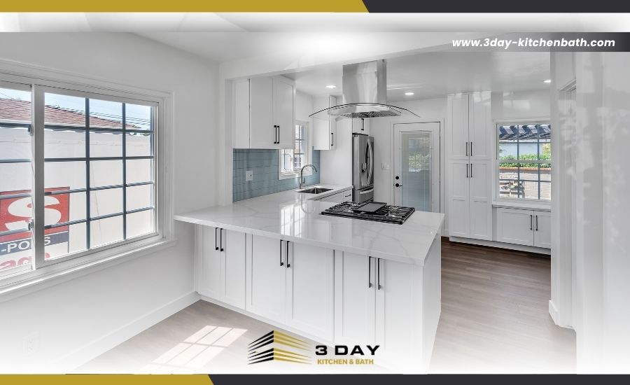 Modern, bright open-concept kitchen renovation with white cabinets, a central island cooktop, and the 3 Day Kitchen & Bath logo.