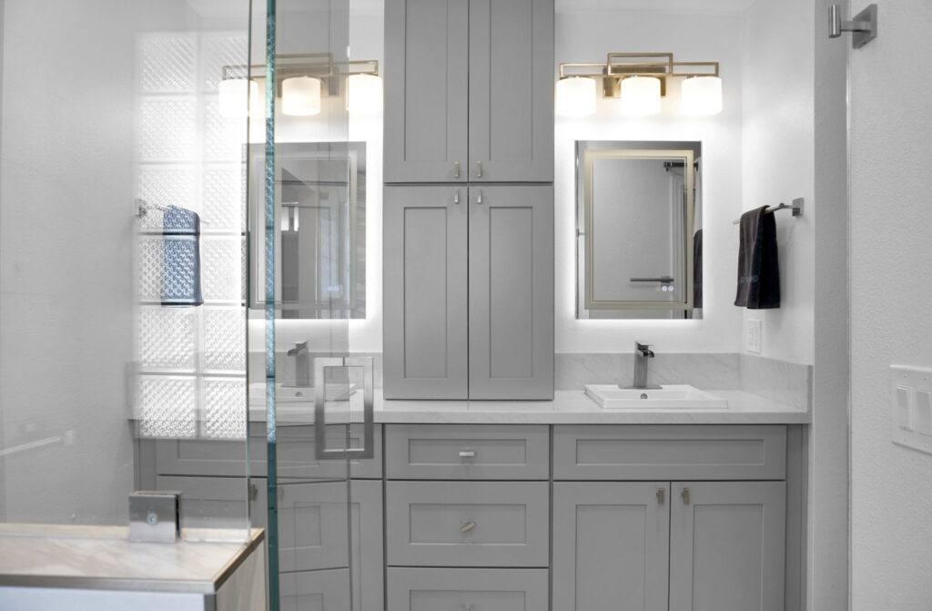 Modern grey bathroom with a tall cabinet wall and double sinks beneath a marble countertop.